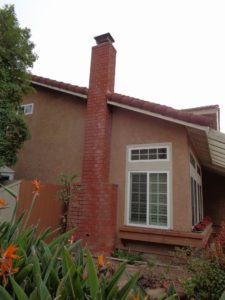A masonry chimney on the exterior wall of a home